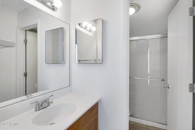 bathroom featuring tile patterned floors, a shower with door, and vanity