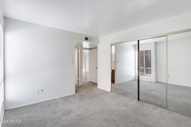 unfurnished bedroom with light carpet and a closet