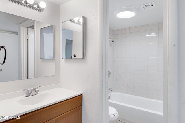 full bathroom featuring vanity, tiled shower / bath combo, and toilet