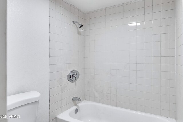 bathroom featuring toilet and tiled shower / bath