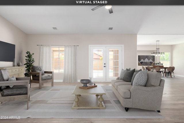 living room with french doors, a chandelier, and light wood-type flooring