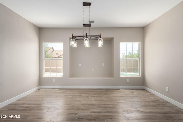 unfurnished dining area with hardwood / wood-style flooring and a chandelier