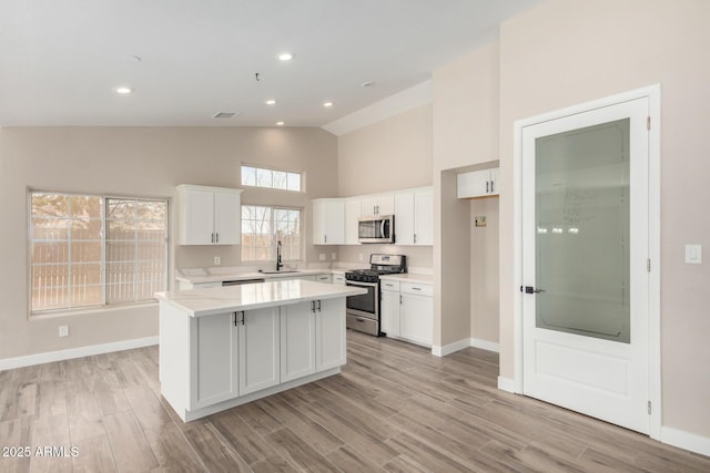 kitchen featuring sink, light hardwood / wood-style flooring, appliances with stainless steel finishes, white cabinetry, and a kitchen island