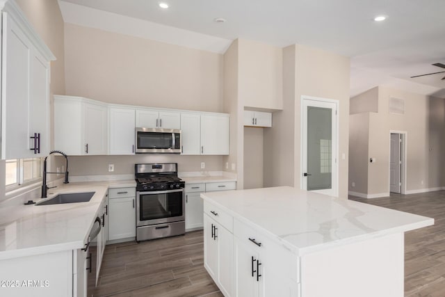 kitchen with stainless steel appliances, white cabinetry, a center island, and sink