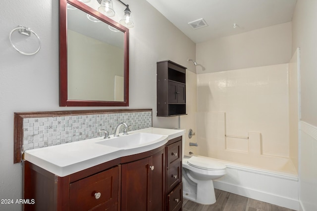 full bathroom with hardwood / wood-style flooring, vanity, tasteful backsplash, shower / washtub combination, and toilet