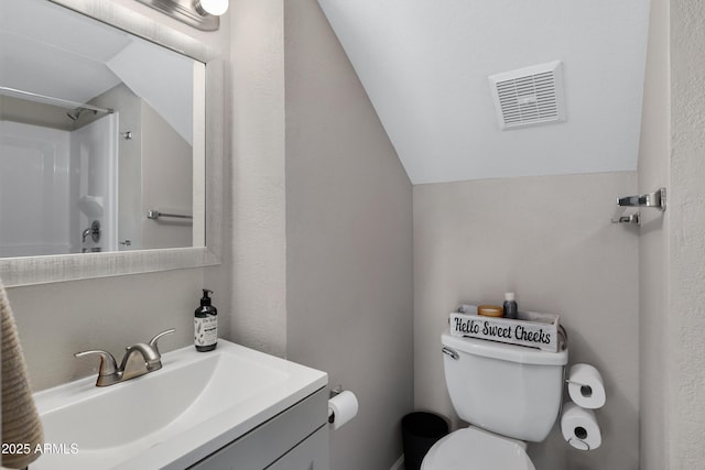 bathroom featuring walk in shower, lofted ceiling, toilet, and vanity