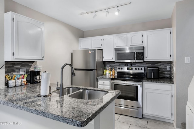 kitchen featuring light tile patterned flooring, tasteful backsplash, kitchen peninsula, stainless steel appliances, and white cabinets