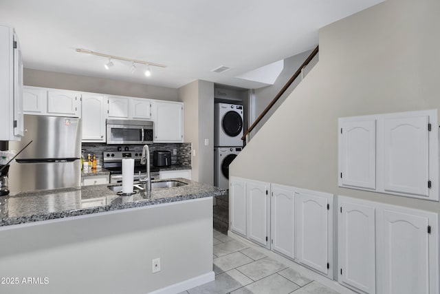 kitchen featuring white cabinetry, appliances with stainless steel finishes, stacked washer and clothes dryer, and sink