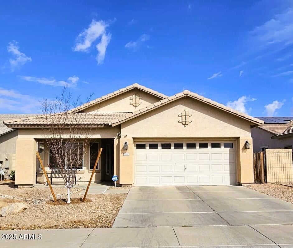 single story home featuring a garage, driveway, a tile roof, fence, and stucco siding