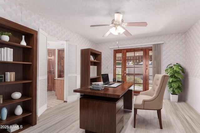 office area with wallpapered walls, ceiling fan, and light wood-style floors