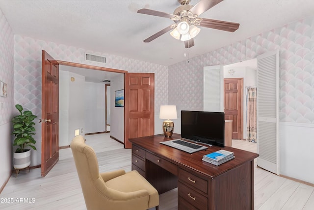 home office with wallpapered walls, light wood-style floors, ceiling fan, and baseboards