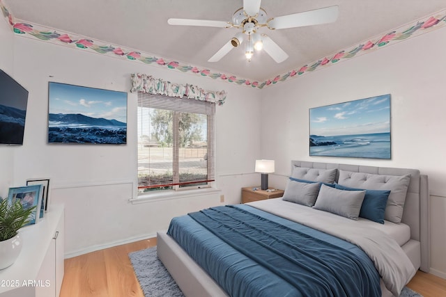 bedroom with light wood-style floors, ceiling fan, and baseboards