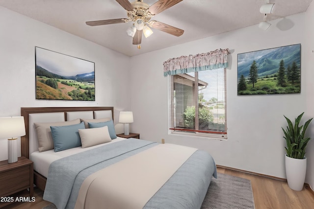 bedroom featuring wood finished floors, a ceiling fan, and baseboards