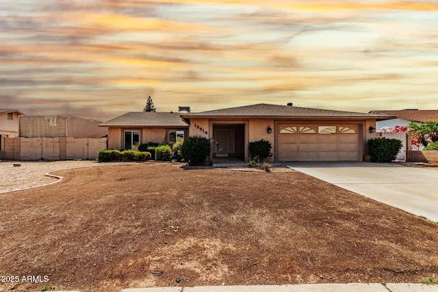 ranch-style house featuring concrete driveway, an attached garage, fence, and stucco siding