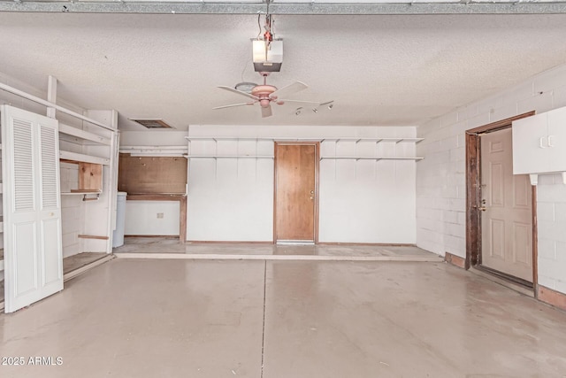 garage with concrete block wall, ceiling fan, and a garage door opener