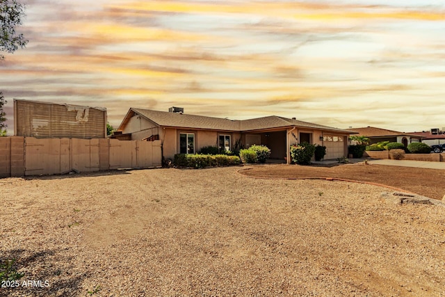 view of front of home with an attached garage, fence, driveway, and stucco siding