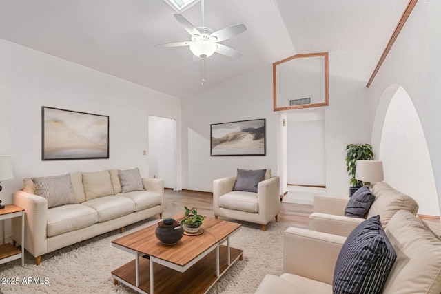 living area with a ceiling fan, lofted ceiling, arched walkways, and light wood-style flooring
