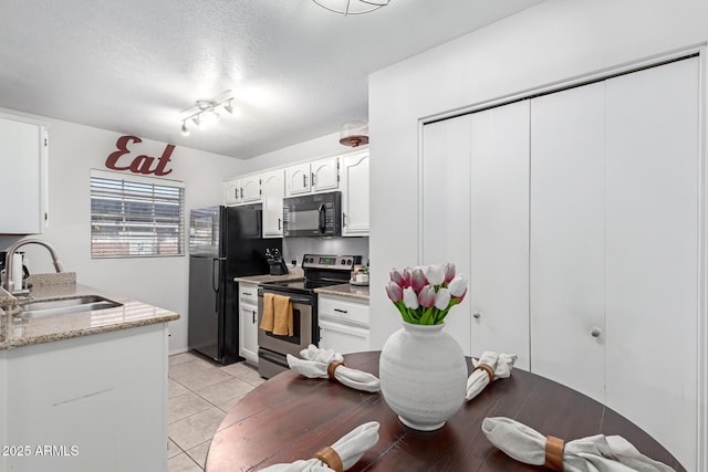 kitchen featuring black appliances, light tile patterned flooring, white cabinets, a textured ceiling, and a sink