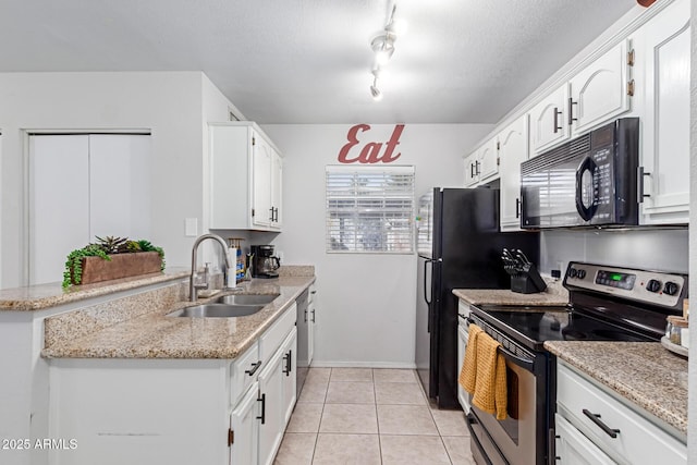 kitchen with light tile patterned floors, light stone counters, appliances with stainless steel finishes, white cabinets, and a sink