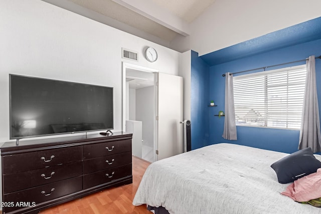 bedroom featuring visible vents, beam ceiling, and wood finished floors