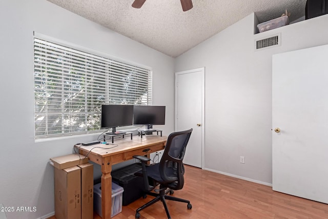 home office featuring visible vents, ceiling fan, lofted ceiling, wood finished floors, and a textured ceiling