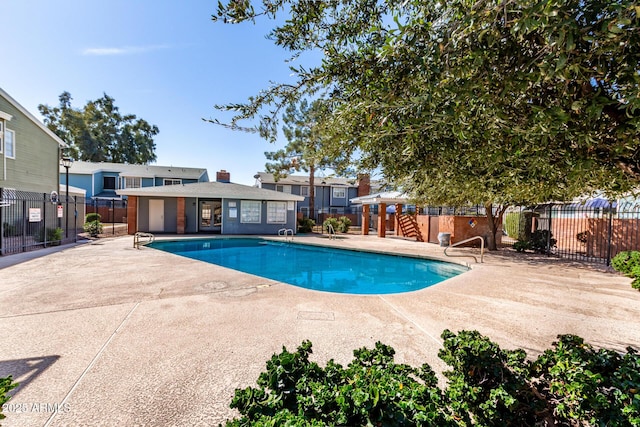 community pool featuring an outbuilding, fence, and a patio area