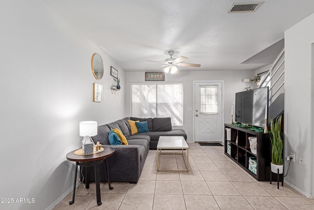 living area with light tile patterned floors, baseboards, visible vents, and ceiling fan