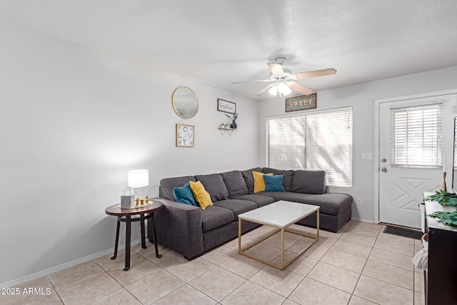 living room with light tile patterned floors, a ceiling fan, and baseboards