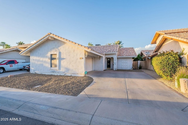 view of front facade featuring concrete driveway, a tiled roof, a garage, and stucco siding