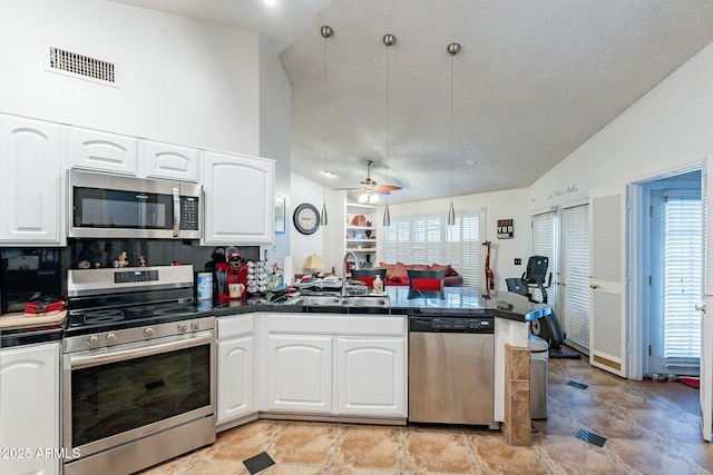 kitchen with visible vents, appliances with stainless steel finishes, a peninsula, white cabinets, and a sink