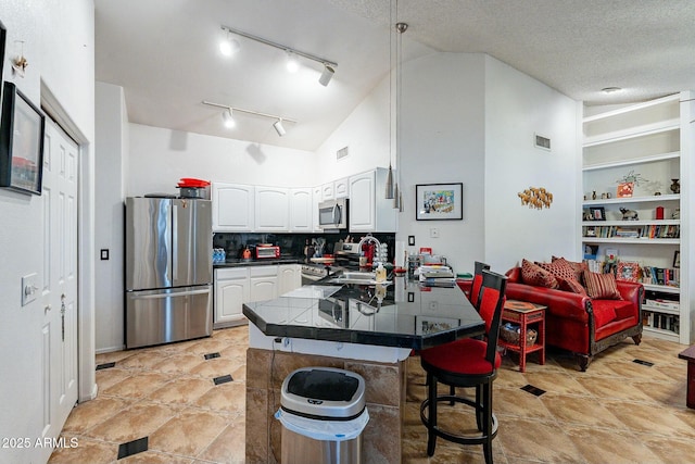 kitchen featuring visible vents, appliances with stainless steel finishes, a peninsula, white cabinets, and a sink