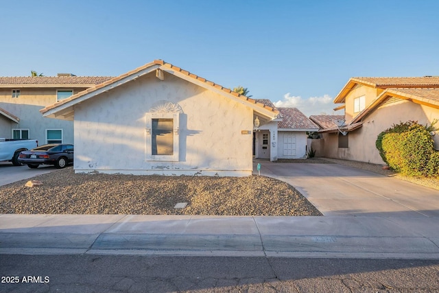 view of front of house featuring concrete driveway, a tiled roof, and stucco siding