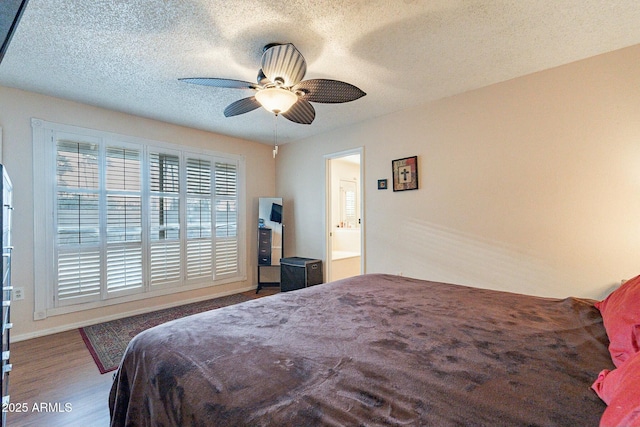 bedroom featuring ensuite bath, a textured ceiling, a ceiling fan, and wood finished floors