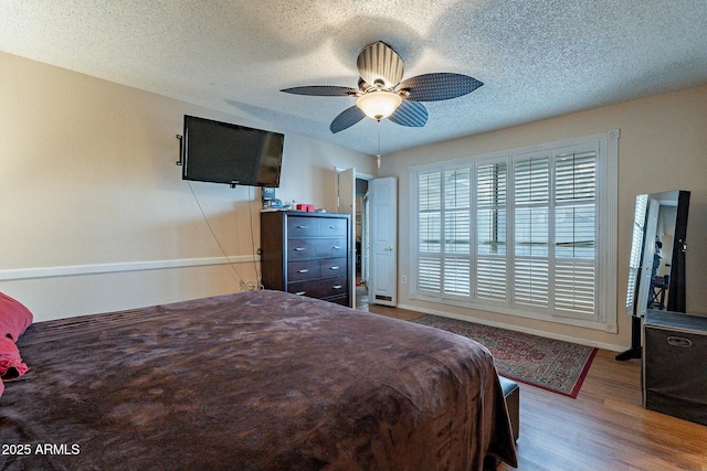 bedroom with baseboards, a textured ceiling, wood finished floors, and a ceiling fan