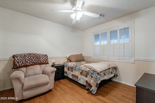 bedroom featuring baseboards, light wood-style flooring, a textured ceiling, and ceiling fan