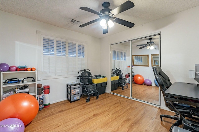 office featuring visible vents, a textured ceiling, ceiling fan, and wood finished floors