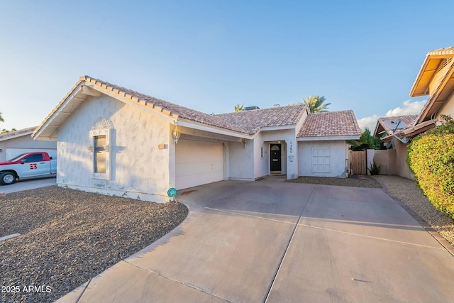 ranch-style house with fence, a tiled roof, concrete driveway, stucco siding, and a garage