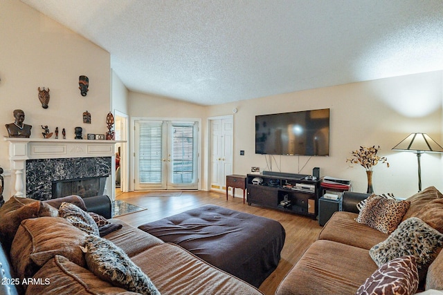 living area featuring a premium fireplace, a textured ceiling, lofted ceiling, and wood finished floors