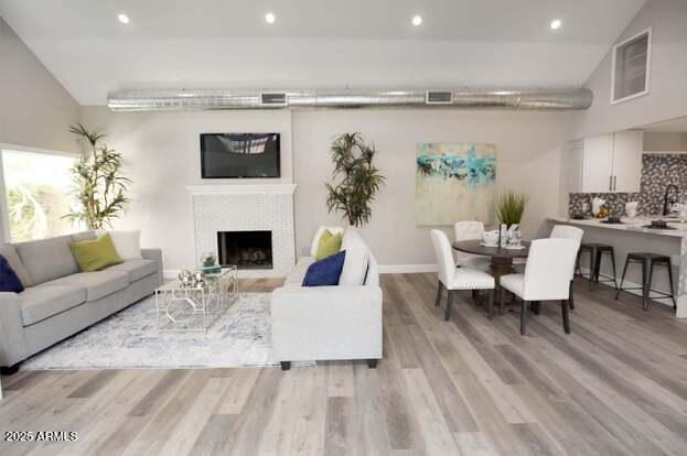7840 N 7th St Unit 15, Phoenix, AZ 85020 - living area featuring light wood-style floors, recessed lighting, a fireplace, and vaulted ceiling