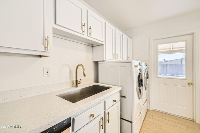 laundry room with washing machine and dryer, a sink, and light wood-style flooring