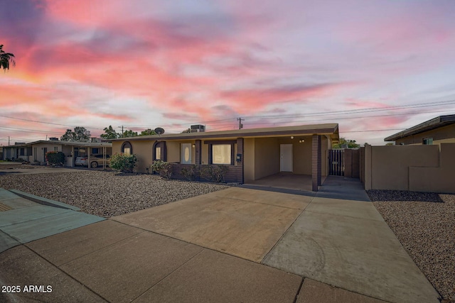ranch-style home with concrete driveway, a carport, and fence