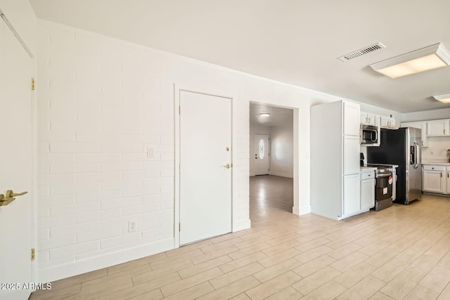 kitchen featuring stainless steel appliances, light countertops, light wood-style floors, white cabinets, and ornamental molding