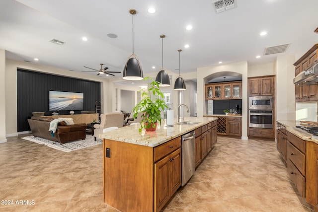 kitchen with stainless steel appliances, ceiling fan, a spacious island, sink, and decorative light fixtures