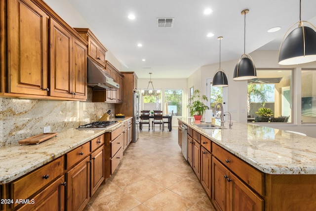 kitchen featuring light stone countertops, tasteful backsplash, stainless steel appliances, sink, and hanging light fixtures