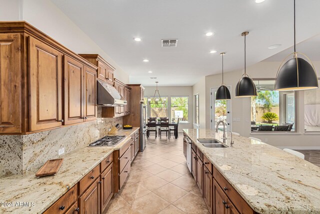 kitchen with light stone countertops, backsplash, ventilation hood, stainless steel appliances, and an inviting chandelier