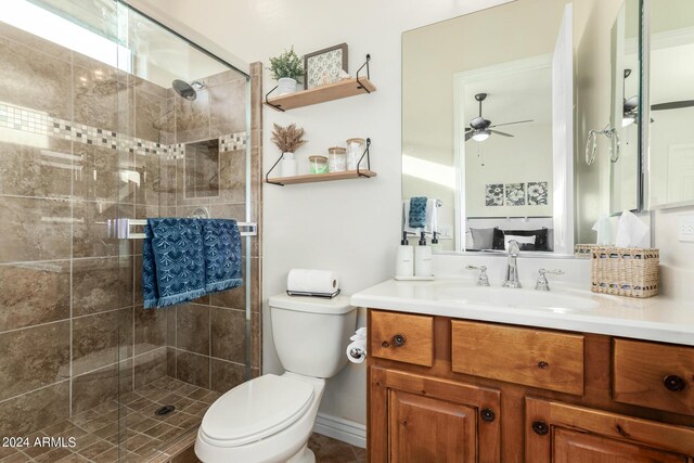 bathroom with vanity, ceiling fan, toilet, and a shower with shower door