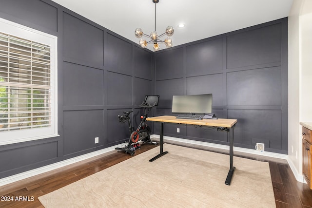 exercise area with dark hardwood / wood-style floors and an inviting chandelier