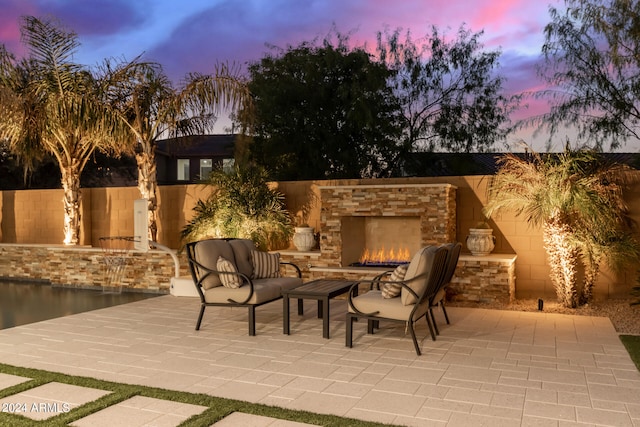 patio terrace at dusk featuring an outdoor stone fireplace