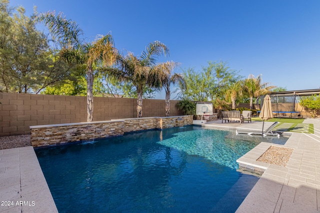 view of pool featuring pool water feature, a patio, and a trampoline