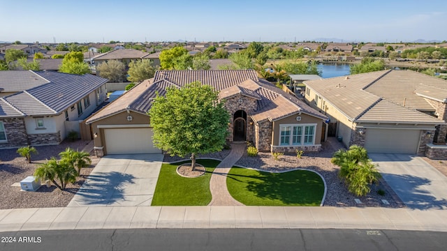 view of front facade featuring a front yard, a garage, and a water view